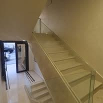 Communal staircase with a frameless glass balustrade and stone treads
