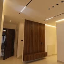 Living space with walnut panelling and a linear ceiling light running the length of the room